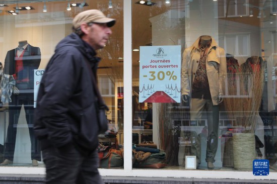   10月31日，一名男子從比利時布魯塞爾一家貼有打折信息的店鋪前走過。新華社記者 趙丁喆 攝