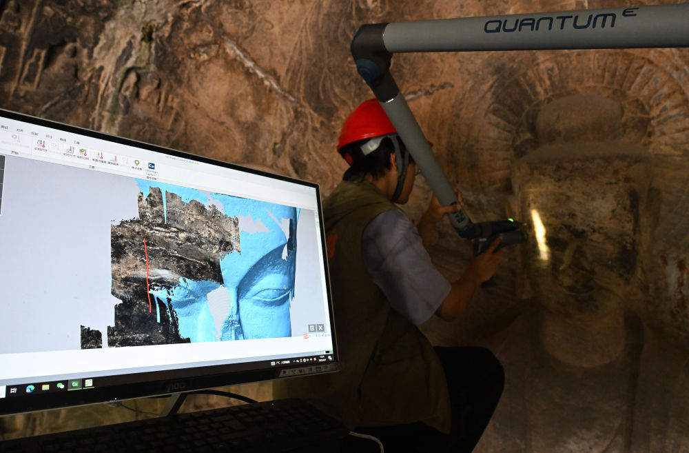 2025年4月9日，武漢大學文化遺產智能計算實驗室團隊成員在魏字洞使用關節臂掃描儀對佛像進行數字化掃描。圖片來源新華社